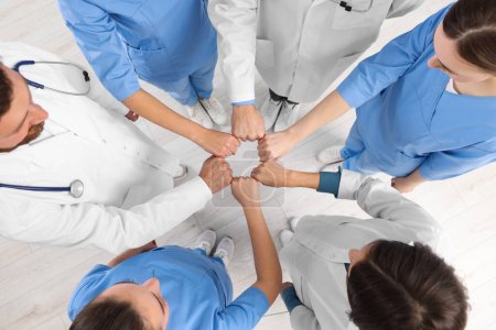 Photo for Team of medical doctors putting hands together indoors, above view - Royalty Free Image