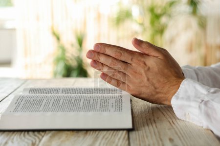 Téléchargez les photos : Homme avec la Bible priant à la table en bois blanc à l'intérieur, gros plan - en image libre de droit