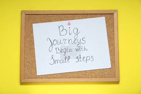 Photo for Corkboard with pinned message Big Journeys Begin With Small Steps on yellow background, top view. Motivational quote - Royalty Free Image
