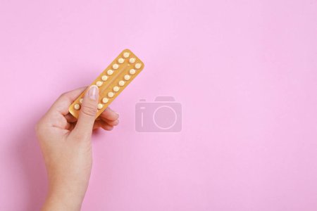 Téléchargez les photos : Femme tenant blister avec des pilules contraceptives sur fond rose, vue de dessus. Espace pour le texte - en image libre de droit