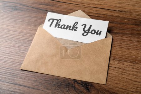 Téléchargez les photos : Enveloppe et carte avec phrase Merci sur table en bois - en image libre de droit