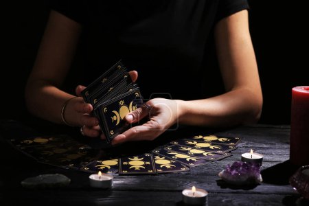 Téléchargez les photos : Soothsayer mélanger des cartes de tarot à table dans l'obscurité. Parler de chance - en image libre de droit