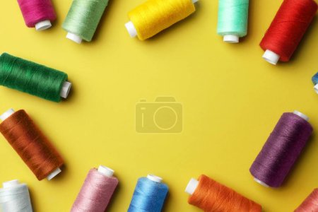 Photo for Frame of colorful sewing threads on yellow background, flat lay. Space for text - Royalty Free Image