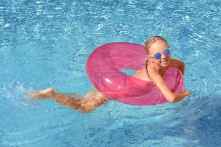 Photo for Cute little girl with inflatable ring in pool on sunny day - Royalty Free Image