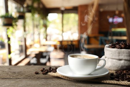 Téléchargez les photos : Coupe de café aromatique et haricots sur table en bois dans le café, espace pour le texte - en image libre de droit