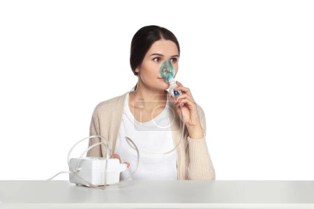 Photo for Young woman using nebulizer at table on white background - Royalty Free Image