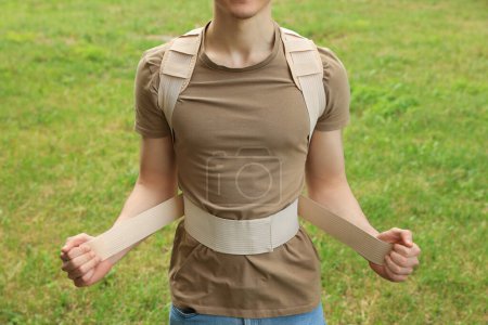 Photo for Closeup view of man with orthopedic corset on green grass outdoors - Royalty Free Image