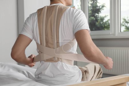 Photo for Closeup of man with orthopedic corset sitting in room, back view - Royalty Free Image