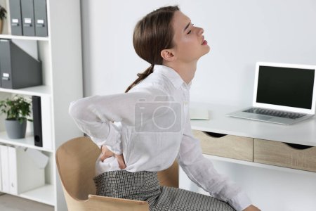 Foto de Mujer que sufre de dolor de espalda mientras está sentada en el cargo. Síntoma de escoliosis - Imagen libre de derechos