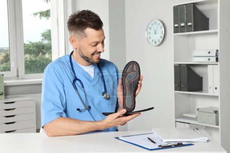 Photo for Handsome male orthopedist showing insoles in hospital - Royalty Free Image
