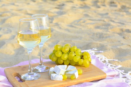 Photo for Glasses with white wine and snacks on beach sand outdoors. Space for text - Royalty Free Image