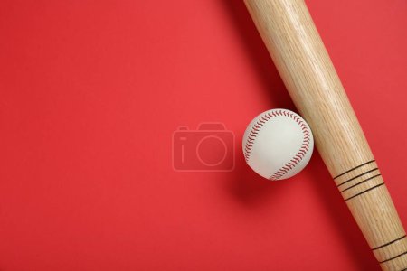 Photo for Wooden baseball bat and ball on red background, flat lay. Space for text - Royalty Free Image