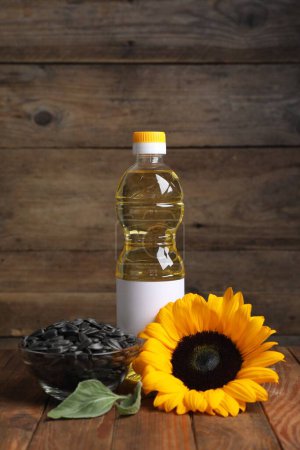 Photo for Sunflower cooking oil, seeds and yellow flower on wooden table - Royalty Free Image