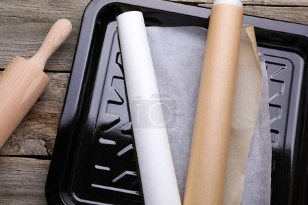 Téléchargez les photos : Rouleaux de papier parchemin dans une plaque à pâtisserie et rouleau à pâtisserie sur une table en bois, pose plate - en image libre de droit