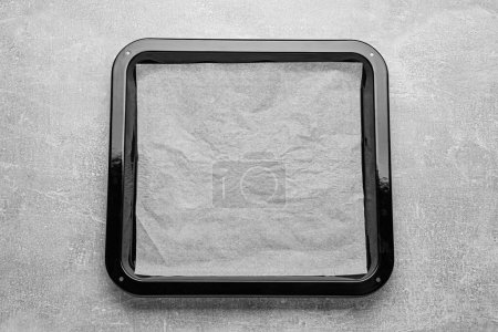 Téléchargez les photos : Plaque de cuisson avec papier parchemin sur table gris clair, vue de dessus. Espace pour le texte - en image libre de droit