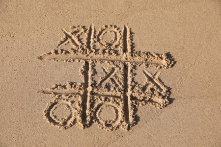 Foto de Tic tac toe juego dibujado en la playa de arena - Imagen libre de derechos