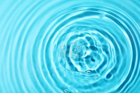 Téléchargez les photos : Vue rapprochée de l'eau avec surface ondulée sur fond bleu clair - en image libre de droit