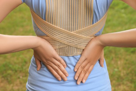 Photo for Closeup of woman with orthopedic corset on blurred background, back view - Royalty Free Image