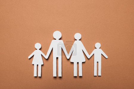 Téléchargez les photos : Figures de famille en papier sur fond brun, vue de dessus. Concept d'assurance - en image libre de droit