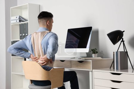 Mann mit orthopädischem Korsett arbeitet im Zimmer am Computer