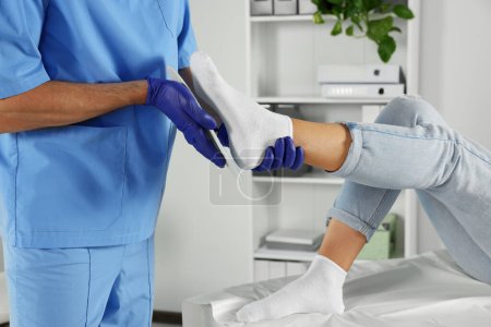 Männlicher Orthopäde passt Einlegesohle am Fuß des Patienten im Krankenhaus an, Nahaufnahme