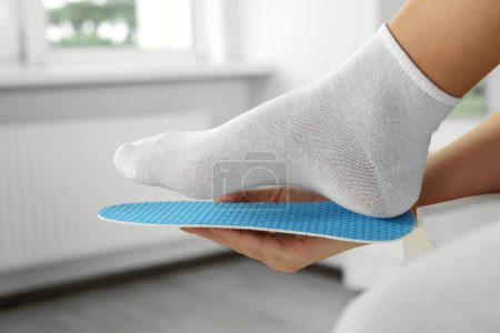 Photo for Woman fitting orthopedic insole to her foot indoors, closeup - Royalty Free Image