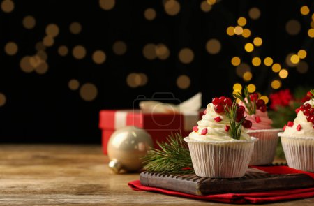 Delicious cupcakes and Christmas decorations on wooden table, space for text