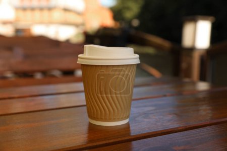 Photo for Takeaway paper cup with coffee on wooden table outdoors - Royalty Free Image