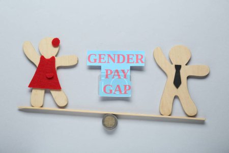 Gender pay gap. Wooden figures of man and woman on miniature seesaw against light grey background