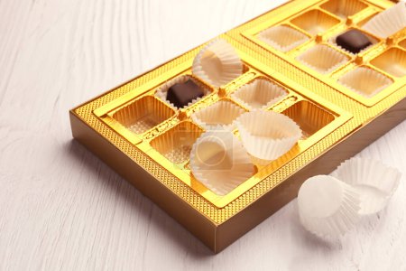 Foto de Caja parcialmente vacía de caramelos de chocolate sobre mesa de madera blanca - Imagen libre de derechos