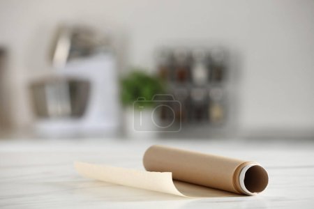 Téléchargez les photos : Rouleau de papier cuisson sur table en marbre blanc sur fond flou à l'intérieur. Espace pour le texte - en image libre de droit