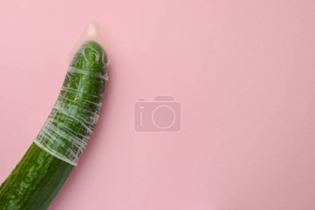 Téléchargez les photos : Concombre avec préservatif sur fond rose, vue du dessus et espace pour le texte. Concept de sexe sûr - en image libre de droit