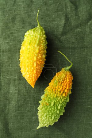 Foto de Melones amargos frescos sobre tela verde oscura, puesta plana - Imagen libre de derechos