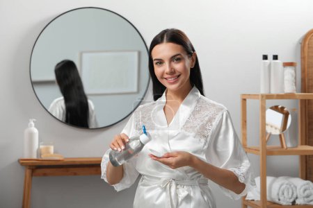 Foto de Mujer joven usando agua micelar y almohadilla de algodón para la eliminación de maquillaje en interiores - Imagen libre de derechos
