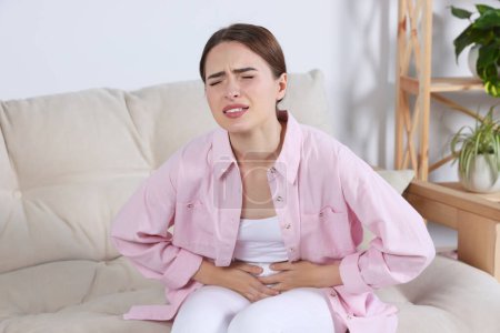 Junge Frau leidet an Blasenentzündung auf dem heimischen Sofa