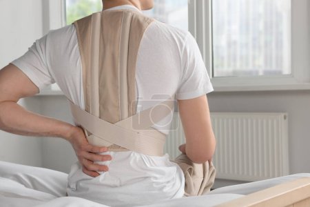 Photo for Closeup of man with orthopedic corset sitting in room, back view - Royalty Free Image