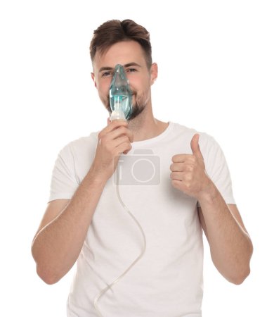 Photo for Man using nebulizer for inhalation and showing thumb up on white background - Royalty Free Image