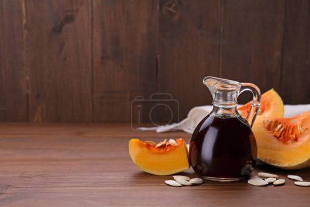Foto de Aceite de semilla de calabaza fresca en jarra de vidrio sobre mesa de madera. Espacio para texto - Imagen libre de derechos