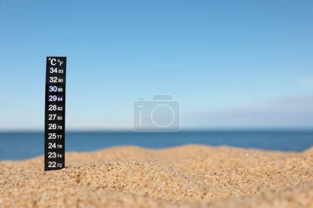 Téléchargez les photos : Thermomètre météo dans le sable près de la mer, espace pour le texte - en image libre de droit