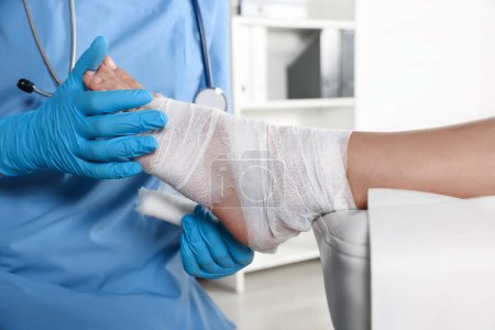 Téléchargez les photos : Doctor applying bandage onto patient's foot in hospital, closeup - en image libre de droit