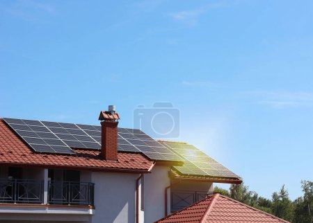 Foto de Casa con paneles solares instalados en el techo bajo cielo azul. Fuente de energía alternativa - Imagen libre de derechos