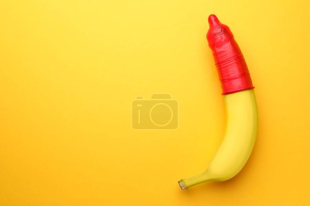 Téléchargez les photos : Banane avec préservatif sur fond orange, vue du dessus et espace pour le texte. Concept de sexe sûr - en image libre de droit