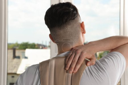 Photo for Man with orthopedic corset near window indoors, back view - Royalty Free Image