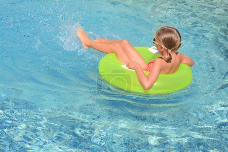 Téléchargez les photos : Petite fille mignonne avec anneau gonflable dans la piscine le jour ensoleillé - en image libre de droit