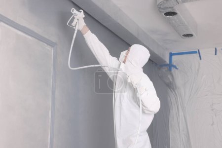 Photo for Decorator dyeing wall in grey color with spray paint indoors - Royalty Free Image