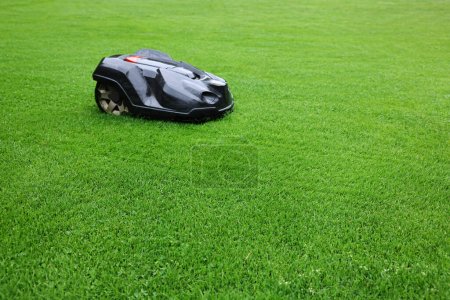 Téléchargez les photos : Tondeuse moderne sur herbe verte à l'extérieur. Espace pour le texte - en image libre de droit