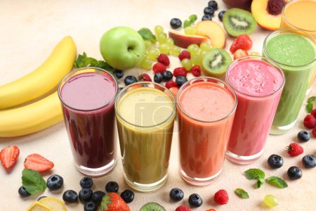 Photo for Fresh colorful fruit smoothies and ingredients on beige table - Royalty Free Image