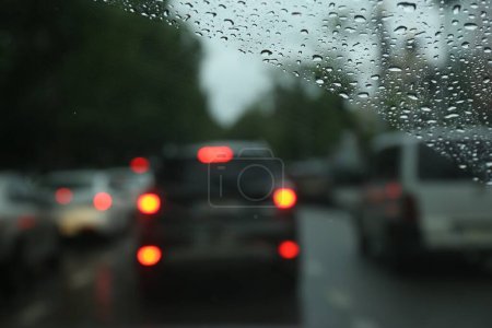 Unscharfe Sicht auf die Straße durch nasses Autofenster. Regenwetter