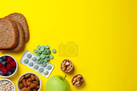 Téléchargez les photos : Nourriture et pilules prébiotiques sur fond jaune, plat. Espace pour le texte - en image libre de droit
