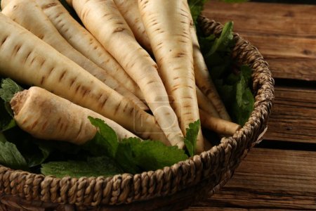 Photo for Fresh ripe parsnips in wicker basket on wooden table, closeup - Royalty Free Image